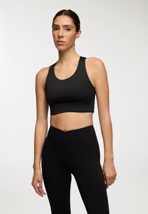 Top corto atletico nero con scollatura tonda e spalline larghe, abbinato a leggings neri a vita alta con dettagli incrociati in vita.