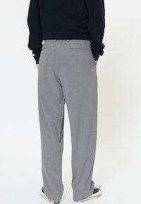 Hallid riidest püksid lõdva istuvusega, lame eesosa ja kaks tagataskut. Kandmiseks tumeda kampsuni ja vabaaja tennistega.