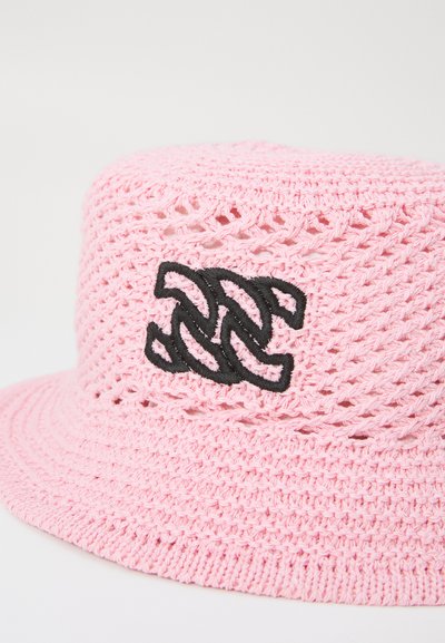 Rosa heklet bucket-hatt med et svart logo-emblem. Åpen vevdesign med bred skjerm og teksturert overflate.
