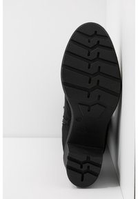 Bottine en suédine noire avec une semelle en caoutchouc texturée présentant un motif en zigzag et une fermeture éclair sur le côté. Taille 37, marque s.Oliver.