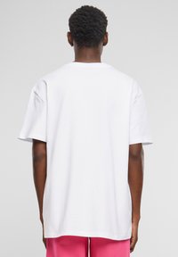 Hvid bomulds T-shirt med rund hals og korte ærmer, der har en afslappet pasform og ingen synlig branding eller mønstre.