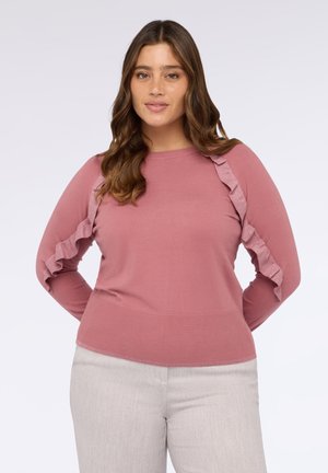 Maglione rosa chiaro con maniche lunghe, caratterizzato da dettagli a rouche testurizzati lungo le maniche. Corpo a tinta unita, colletto rotondo, orlo a coste. Abbinato a pantaloni grigi chiari.