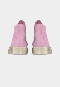 Ροζ υφασμάτινα ψηλά αθλητικά παπούτσια με φθαρμένες λευκές λαστιχένιες σόλες και το λογότυπο Converse All Star στο πίσω μέρος, προβολή από πίσω.