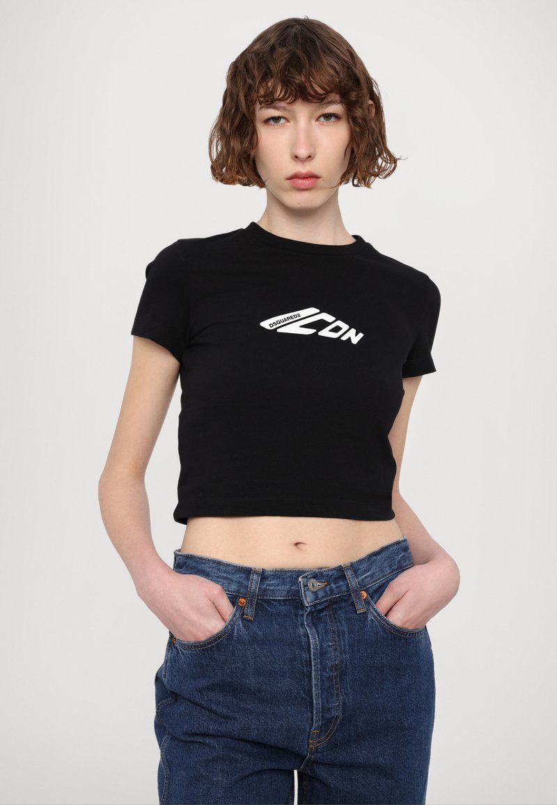 Schwarzes kurzärmliges, kurzes T-Shirt mit weißem "DSquared2"-Logo, kombiniert mit blauen hochgeschnittenen Jeans. Glattes Material und lässiger Schnitt.
