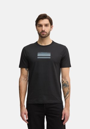 T-shirt in cotone nero con una striscia orizzontale blu sfumata al centro e il testo "Calvin Klein". Design a maniche corte e collo rotondo.