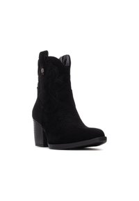 Botín de tobillo de ante negro con costuras decorativas, puntera afilada y tacón apilado. Acentuado con un pequeño botón metálico en el lateral.