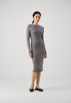 Vestido midi gris, acanalado, de manga larga con cuello redondo y aberturas laterales, combinado con zapatos planos negros de punta. Textura suave.