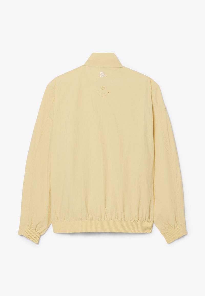 Beige lichtgewicht jas met lange mouwen, geribde manchetten en zoom, en een klein wit logo gecentreerd vlak bij de bovenste achterkant van de kraag.