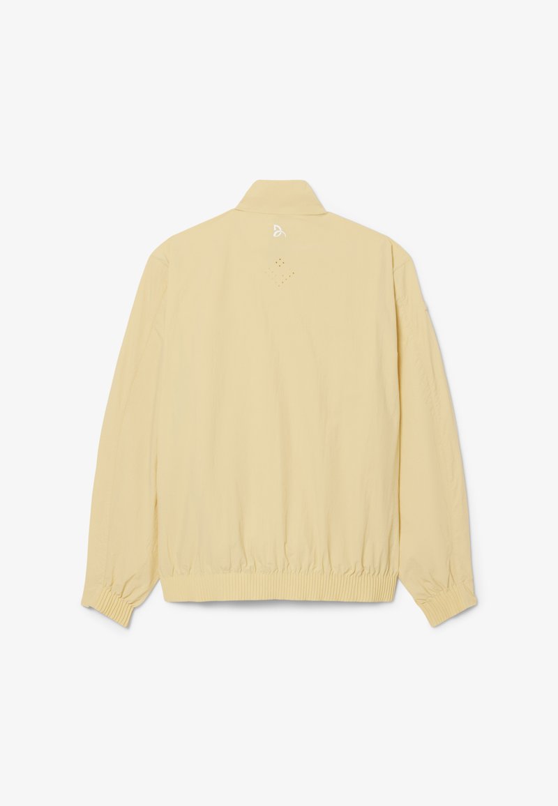 Beige lichtgewicht jas met lange mouwen, geribde manchetten en zoom, en een klein wit logo gecentreerd vlak bij de bovenste achterkant van de kraag.