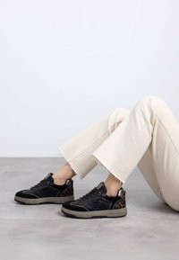 Zapatillas negras con estampado de leopardo, confeccionadas en materiales de ante y cuero, con punta redonda, diseño con cordones y una suela gruesa y texturizada.