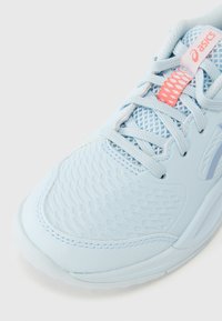 Αθλητικό παπούτσι ανοιχτού γαλάζιου χρώματος με υφή στην επιφάνεια, λεπτομέρειες από δίχτυ και αντίθετες ροζ πινελιές στα κορδόνια και τη σήμανση.