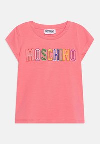 Różowa koszulka z krótkim rękawem o okrągłym dekolcie. Posiada kolorowy napis "MOSCHINO" w zabawnym kroju, wykonana z miękkiego materiału.