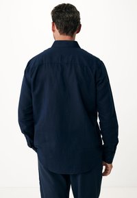 Maglietta a maniche lunghe blu navy con colletto, polsini con bottoni e orlo dritto. Tessuto morbido con superficie liscia, senza motivi visibili.