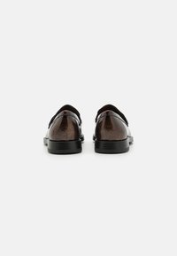 Sapatos de couro castanho com acabamento texturizado, design elegante, solas de borracha preta e bico arredondado. Apresentados sem atacadores e na vista traseira.