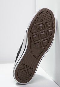 Černá plátěná podešev tenisek s texturovaným hnědým gumovým dnem. Obsahuje bílý gumový okraj a diamantový vzor pro lepší přilnavost.