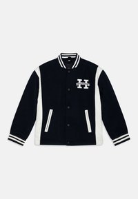 Námornícky modrá varsity bunda s bielymi bočnými panelmi, žebrovanými manžetami a golierom. Obsahuje vyšívané logo "H" a dve predné vrecká.