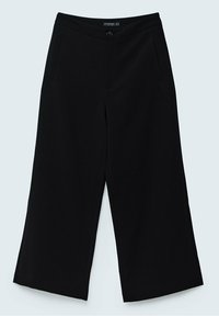 Pantalon noir ample et raccourci avec poches latérales, fermeture par boutons à l'avant et étiquette sur la ceinture sur un fond clair.