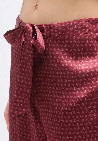 Bordó satīna bikses ar sasietu jostiņu, tām ir smalks atkārtots raksts. Gluda tekstūra ar spīdīgu virsmu.