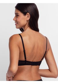 Black bra featuring adjustable straps, hook-and-eye closure, and a soft textured fabric with a sheer back design.