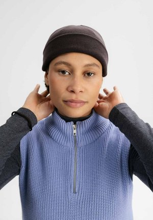 Knitted gray beanie, ribbed texture; light purple sleeveless sweater with high collar and zipper detail. Dark long-sleeve top underneath.