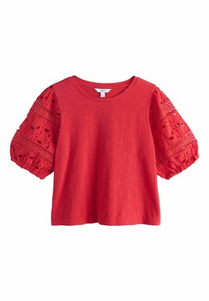Rød kortærmet bluse med rund halsudskæring og puffede ærmer i hulmønster med blomsterudskæringer.