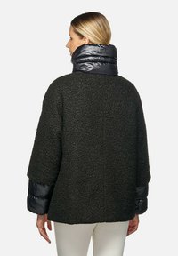 Giacca esterna nera con una trama testurizzata, colletto e maniche imbottiti neri. Il design presenta una vestibilità ampia e una schiena semplice.