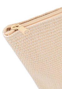 Funda tejida beige con un acabado texturizado. Presenta un cierre de cremallera y un sutil detalle de costura a lo largo del borde superior. Ligera y compacta.