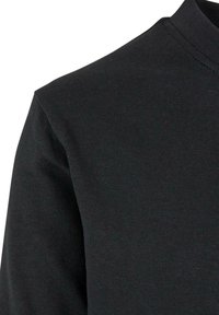 Prim-plan al unui material din bumbac negru care arată cusătura de la umăr și gulerul rotund al unui tricou simplu.