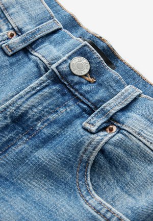 Lichtblauwe spijkerbroek met een zilveren knoop, koperen klinknagels en bruine stiksels. Inclusief een klein zakje en een riemlus.