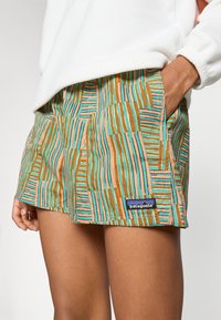 Pantalones cortos Patagonia con un patrón geométrico multicolor en tonos azul teal, naranja y marr�ón, que incluyen bolsillos laterales y un detalle de logo bordado.