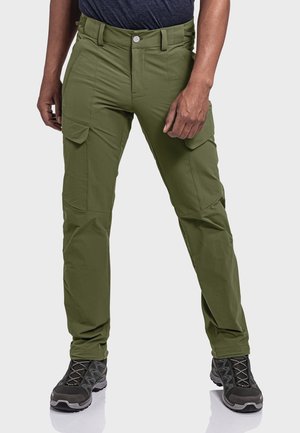Olivgrüne Cargo-Hosen aus flexiblem Material, mit mehreren Taschen, einem Reißverschluss und einer schmalen Passform, kombiniert mit schwarzen Wanderschuhen.