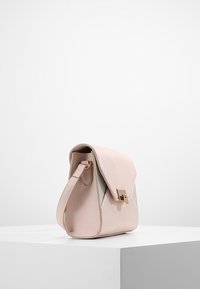 Borsa a mano in similpelle rosa con una forma strutturata, chiusura a patta, hardware in tono oro e un pannello laterale verde chiaro a contrasto.