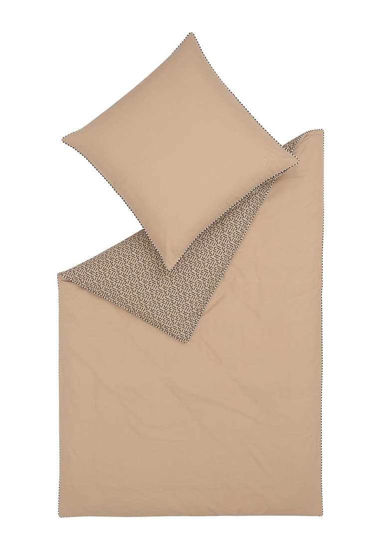 Juego de cama que presenta un edredón beige sólido con un lado inferior de patrón geométrico y una almohada a juego, destacada con costura decorativa.
