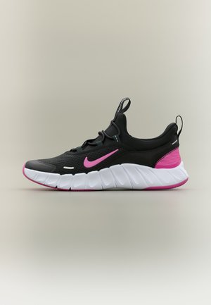 Sort og lyserød Nike sportssko med tyk hvid segmenteret sål, lyserødt swoosh-logo og trækketab på tunge og hæl.