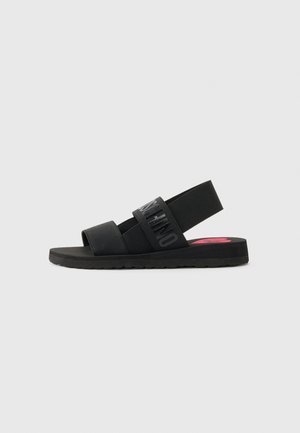 Sandali neri con due cinturini regolabili, caratterizzati da dettagli con logo embossato. Tacco chiuso e suola texturizzata per una maggiore aderenza. Insole rosa in accento.