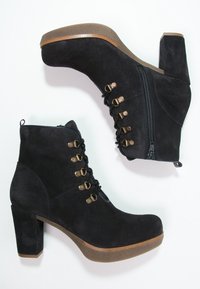 Czarne zamszowe botki za kostkę z grubym obcasem, sznurowanym przodem i bocznym zamkiem. Zauważalne mosiężne elementy oraz matowe wykończenie o fakturze.