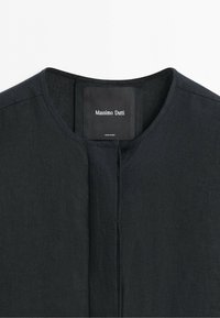 Czarna koszulka z okrągłym dekoltem, ukrytą plisą z przodu oraz metką marki Massimo Dutti wszytą od wewnątrz kołnierza.