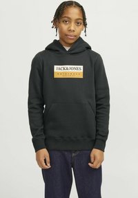 Sudadera negra hecha de tela suave, que cuenta con un bolsillo frontal y un logo gráfico en dorado y blanco en el pecho. Corte clásico con puños de canalé.
