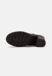 Suela negra con un patrón de agarre texturizado, tacón ligeramente elevado y superficie lisa. Diseño minimalista, adecuado para varios estilos de calzado.