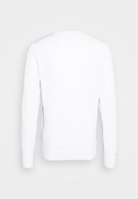 Sweat-shirt blanc uni à manches longues avec col rond, vu de dos sur un fond gris clair.