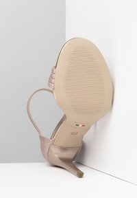 Pink-beige High Heel Sandale mit glänzender Textur, dünnem Knöchelriemen und spitzer Zehenpartie. Verfügt über eine gerillte Sohle und italienische Markenkennzeichnung.