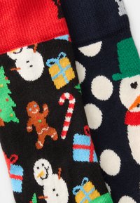 Meias de malha com um design preto contendo bonecos de neve, árvores e homens de gengibre de um lado; azul marinho com bolinhas brancas e um boneco de neve do outro lado.