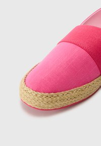 Rosa leirvevde espadrillos med såle av jute, med en bred stoffrem over toppen og en glatt tekstur på overflaten.