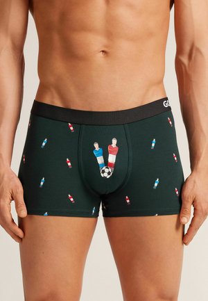 Männliche grüne Boxershorts mit einem bedruckten Design von Fußballspielern und einem Ball, ausgestattet mit einem schwarzen elastischen Bund.