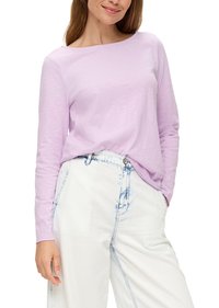 Langärmliges lilafarbenes Oberteil aus leichtem Stoff mit weitem Ausschnitt, kombiniert mit hochgeschnittenen weißen Jeans und hellblauen Akzenten.