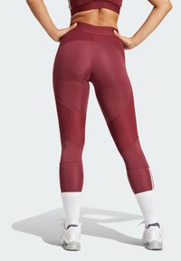 Bordeaux leggings med høj talje, strukturerede paneler og kontrasterende detaljer. Stilet med hvide sportsstrømper og sneakers.
