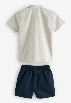 Kortærmet skjorte i lys beige med subtile striber, parret med mørkeblå elastiske shorts med talje, glat tekstur og klassisk pasform.