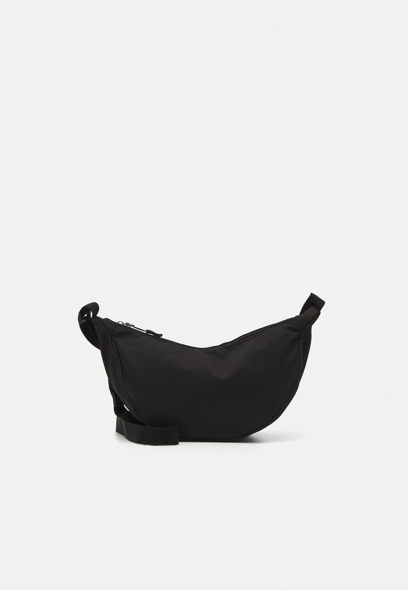 Bolsa de ombro preta em tecido com forma curva, fecho em zíper, alça ajustável e um pequeno bolso lateral para armazenamento adicional.