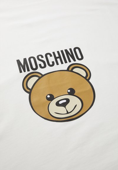 Balta medvilninė marškinėliai su dideliu ruda meška grafika ir tekstu „MOSCHINO“ viršuje, parašytu ryškiu juodu šriftu. Pati medžiaga glotni.