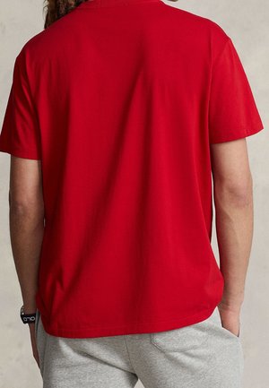 T-shirt rouge à manches courtes en coton avec une coupe décontractée. Le dos présente un design uni sans logos ni motifs.